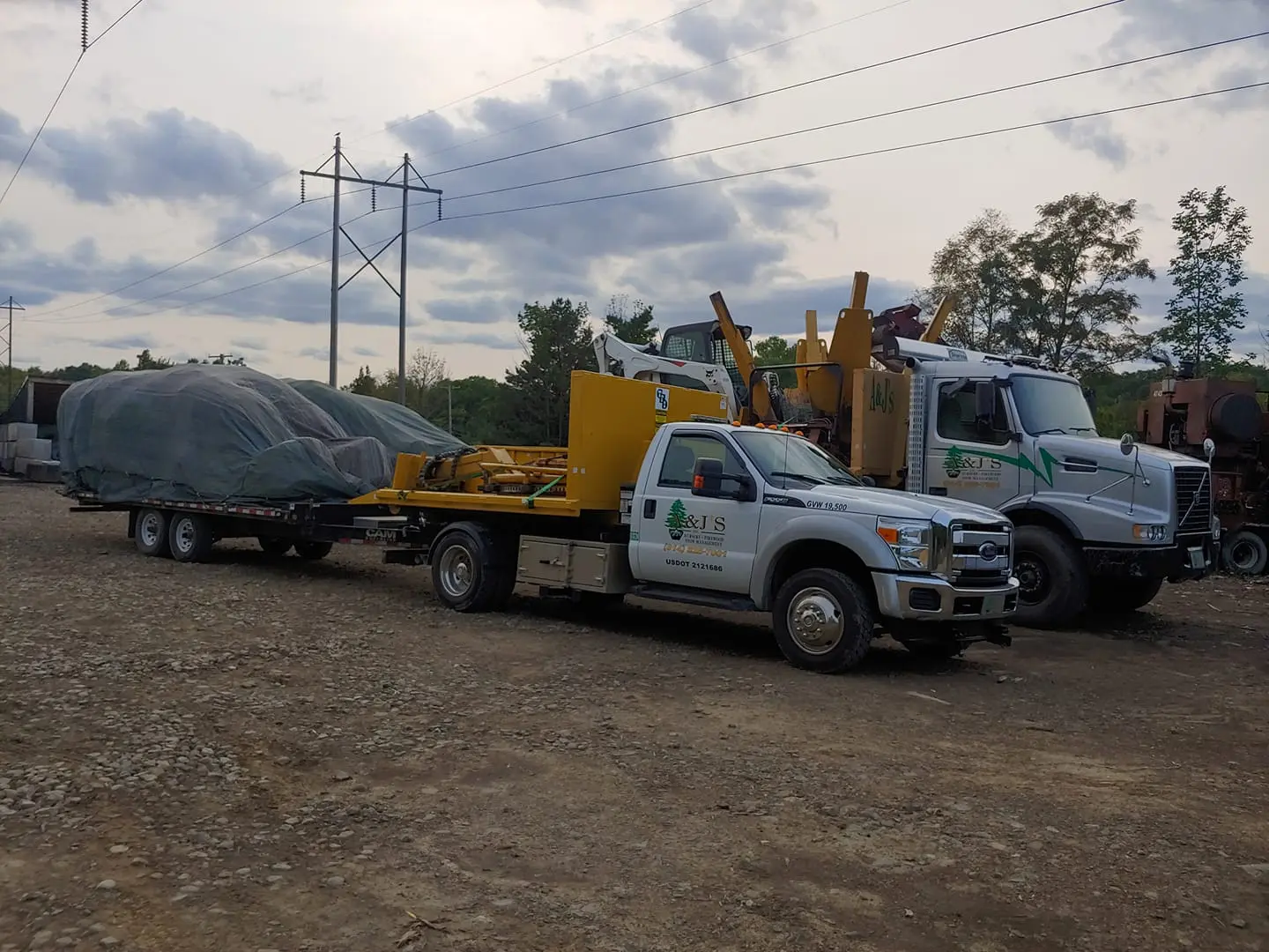 Truck with trailer parked on dirt lot.